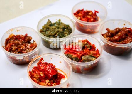 Aneka Sambal Indonesia. Fünf Arten von indonesischen würzigen Würze in Untertassen von Mini-Schüssel überzogen. In der Nähe befindet sich ein Korb mit frischen Chilischoten. Stockfoto