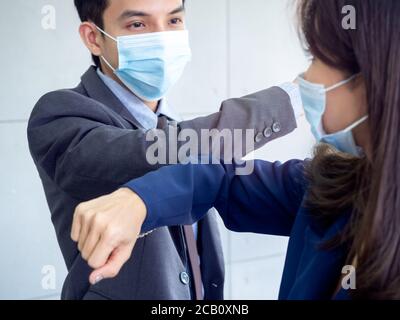 Ellenbogenstoß. Geschäftsmann und Geschäftsfrau tragen schützende Gesichtsmaske und verwenden Ellbogen in Gruß stoßen. Sichere Grüße. Neue Art zu grüßen, statt Stockfoto