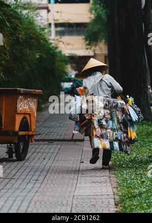 Ho Chi Minh Stadt, Vietnam - 29. Juli 2020: Vietnamesische Frauen tragen nicht la, Straßenhändler, Verkauf von Souvenirs und verschiedene Waren, zu Fuß auf den s