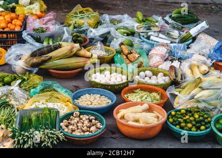 Auf dem Bürgersteig auf einem lokalen Markt in Vietnam, eine Menge Gemüse an einem Stand wie Auberginen, Papaya, Salat, Eier, Bambussprossen, Bittermelone, c Stockfoto