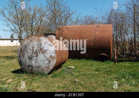 Zwei alte verlassene rostige Fässer liegen im Freien auf dem Gras. Stockfoto