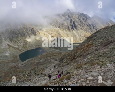 Panorama von Bystra lavka 2300m mit dem Bergsee Capie und Okruhle pleso mit Wanderer klettern, Mlynicka dolina und Gipfel Strbsky stit 2381m Stockfoto