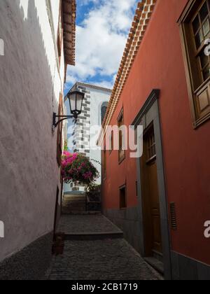 Schmale Straße im alten Dorf garachico mit traditionellen roten und Weiße Häuser latern Blumen und blauen Himmel Stockfoto
