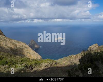 Blick auf Felsen im Meer El Draguillo mit grünen Hügeln und dramatischen blauen Himmel weißen Wolken in anaga Berg, teneriffa kanarische Insel spanien Stockfoto