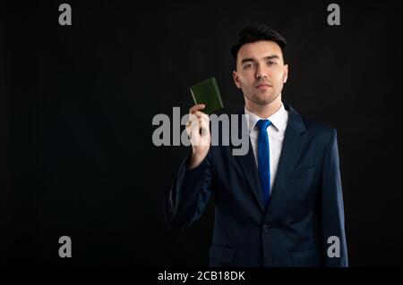 Porträt eines Geschäftsmanns mit blauem Business-Anzug und Krawatte Zeigt Brieftasche isoliert auf schwarzem Hintergrund mit Copy Space Werbung Bereich Stockfoto