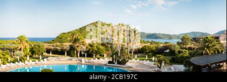 Mediterrane Landschaft. Wasserpool mit Sonnenliegen und Sonnenschirmen. Luxuriöser Panoramablick auf das Mittelmeer. Sardinien. Italien. Stockfoto