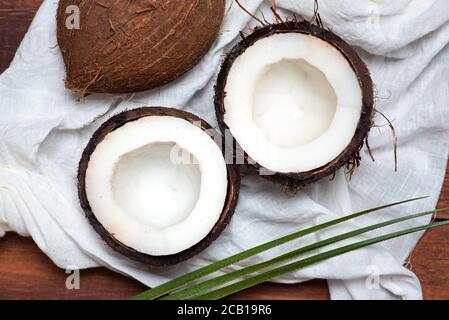 Halbierte offene Kokosnussfrüchte auf einem Holztisch Draufsicht Stockfoto
