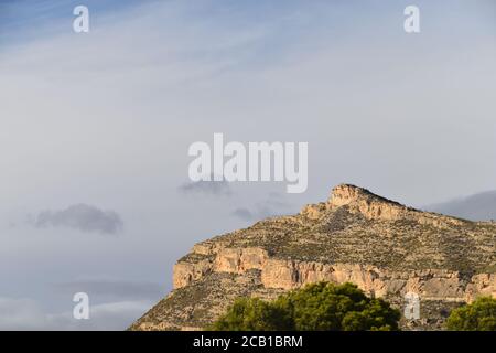 Hoher Berg bedeckt mit Grün und schimmert unter der Bewölkung Himmel Stockfoto