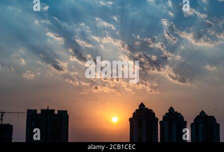 Mumbai, Maharashtra, Indien - März 2020: Sonnenstrahlen scheinen durch die Wolken hinter den hohen Gebäuden der Vorstadt Kandivali in Mumbai. Stockfoto