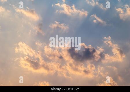 Sonnenstrahlen brechen durch Wolken in einem blauen Himmel Stockfoto