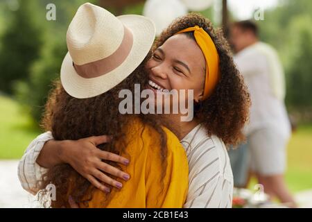 Porträt der jungen afroamerikanischen Frau umarmt Freund und lächelt fröhlich während draußen Party im Sommer genießen Stockfoto