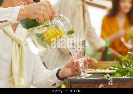 Nahaufnahme eines nicht erkennbaren Mannes, der Limonade in eine Glastasse gießt, während Sie im Sommer eine Party im Freien genießen und Platz kopieren Stockfoto
