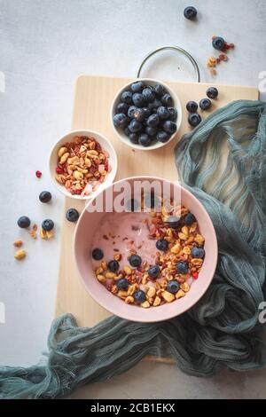 Rosa Joghurt mit Flocken und Heidelbeeren für das Sommerfrühstück, flach Lay-Stil Stockfoto