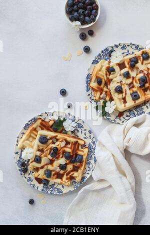 Food flat lag mit hausgemachten Waffeln und Heidelbeeren auf einem grauen Hintergrund, von oben geschossen Stockfoto