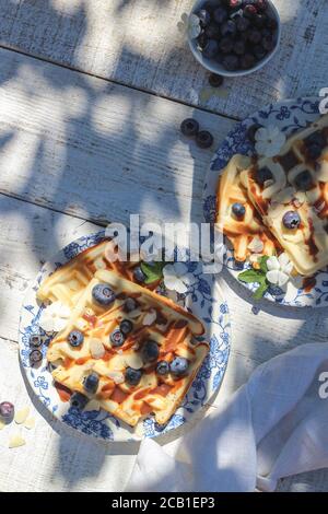 Flatlay mit Waffeln und Heidelbeeren auf einem Gartentisch erschossen Unter einem harten Licht Stockfoto