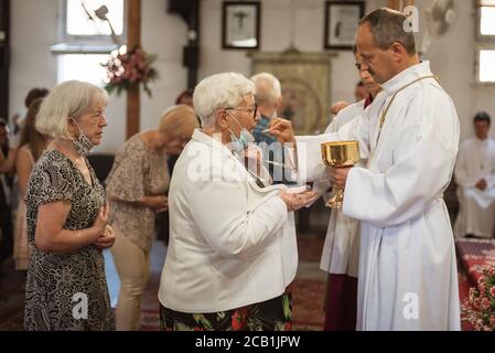 LUBIN, POLEN - 19. JULI 2020. Heilige Messe in der Kirche. Der Priester gibt heilige Kommunion. Aufgrund der Pandemie Covid-19 Coronavirus Menschen haben Gesicht Mas Stockfoto