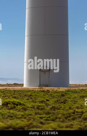 Blick von der Basis des Turms einer Windkraftanlage, mit Zugangstür zum Inneren der Turbine, natürliche Landschaft als Hintergrund Stockfoto