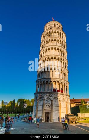 Schöne Porträtaufnahme des berühmten schiefen Turms von Pisa mit Eingangstür an einem schönen Tag in der Dämmerung mit einem blauen Himmel, und die Sonne scheint auf dem weißen... Stockfoto