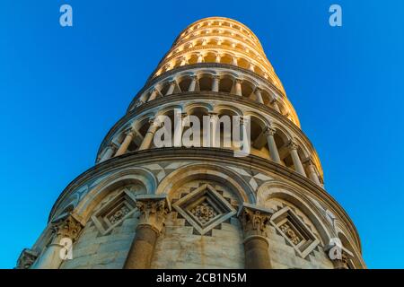Tolle Nahaufnahme mit Blick auf den schiefen Turm von Pisa mit einem blauen Himmel im Hintergrund. Die Sonne scheint auf dem oberen Teil des berühmten Glockenturms... Stockfoto