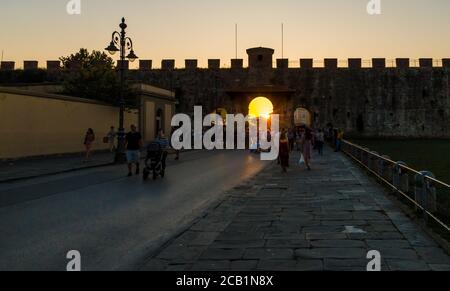 Schöner Blick auf die mittelalterliche Mauer der Piazza dei Miracoli in Pisa bei Sonnenuntergang. Touristen treffen sich am Eingang des berühmten Platzes, ein UNESCO... Stockfoto