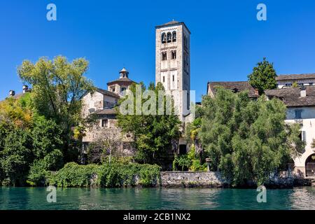 Mittelalterlicher Turm und altes Kloster unter grünen Bäumen auf der kleinen Insel San Giulio am ortasee im Piemont, Norditalien. Stockfoto