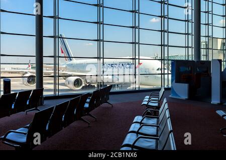 Stühle in leerer Abflughalle und A380-Flugzeug hinter dem Glasfenster im Hintergrund am Flughafen Charles De Gaulle in Paris. Stockfoto