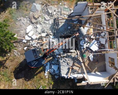 Zerstörung des alten Hauses mit Eimer Bagger im Dorf. Eine zerstören Die Zerstörung des alten Hauses der Bagger. Luftaufnahme Stockfoto