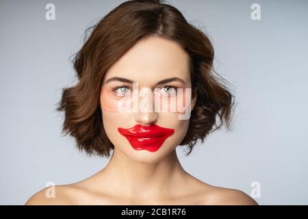 Charmante junge Frau mit Kollagen Lip Patch und unter-Augen-Patches Stockfoto