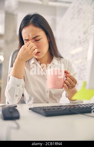 Junge müde Büroangestellte faltete ihre Stirn Stockfoto