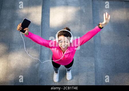 Draufsicht auf emotionale Joggingweibchen mit Smartphone Stockfoto