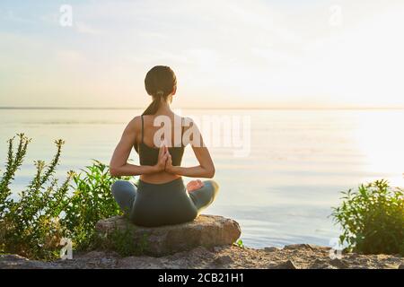 Sportliche junge Frau tut Reverse Gebet Pose im Freien durch die Meer Stockfoto
