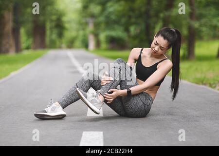 Sportverletzung. Asiatische Mädchen Leiden Unter Knöchelschmerzen Nach Dem Joggen Im Park Stockfoto