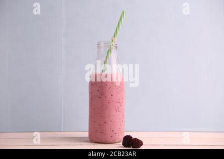 Das Glas des Beerenmoothie mit dem Stroh und mit Zwei Beeren auf dem Tisch Stockfoto