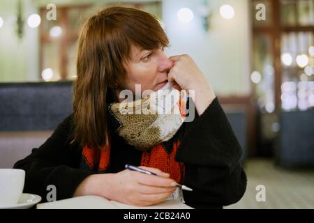 Frau im Café schreibt in Tagebuch, Bullet Journal. Langsames Leben, soziale Entgiftung, freiberuflich, Planung, selbst-Immersion, als Single-Konzept. Stockfoto