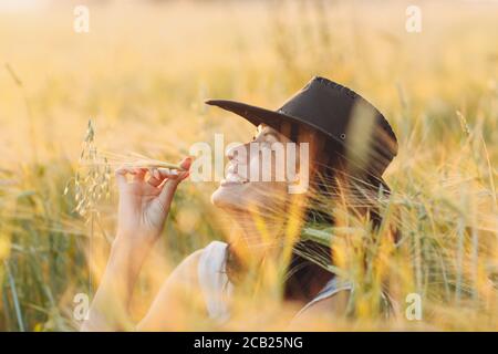 Frau Bäuerin im Cowboy Hut auf dem landwirtschaftlichen Feld bei Sonnenuntergang Stockfoto