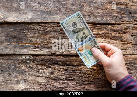 Der Mann zahlt. Hält eine hundert-Dollar-Rechnung in seiner Hand Stockfoto