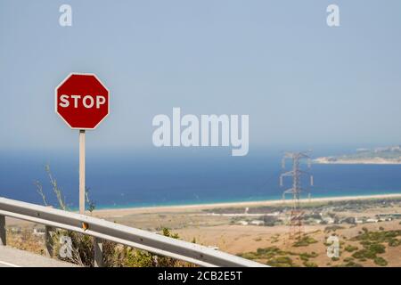 Strassenschild Stop, auf einer spanischen Strasse, N-340. Strand von Tarifa im Hintergrund, Cadiz, Spanien. Stockfoto