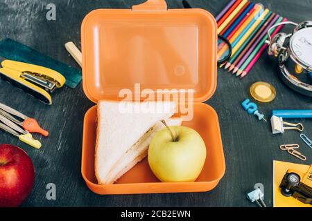 Draufsicht auf die Lunchbox mit Sandwiches und reifen Äpfeln In der Nähe der Schule Schreibwaren auf schwarzer Kreidetafel Stockfoto