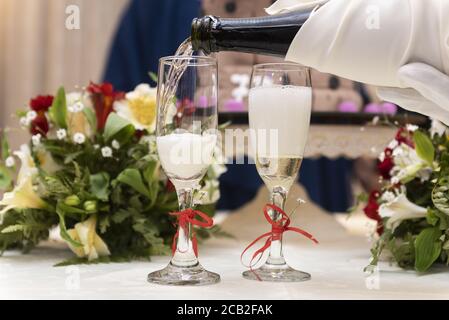 Während einer Hochzeit gießt der Kellner Champagner auf die Gläser Stockfoto