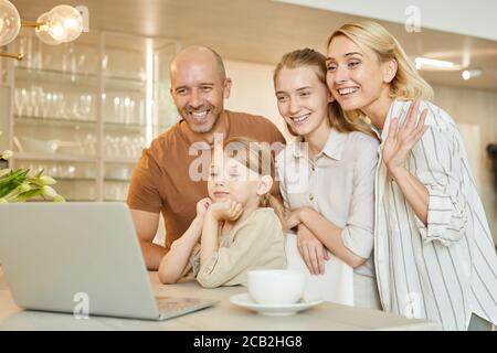 Warm-getönte Porträt der modernen glücklichen Familie winken an der Kamera, während im Video-Chat mit Verwandten sprechen, kopieren Raum Stockfoto