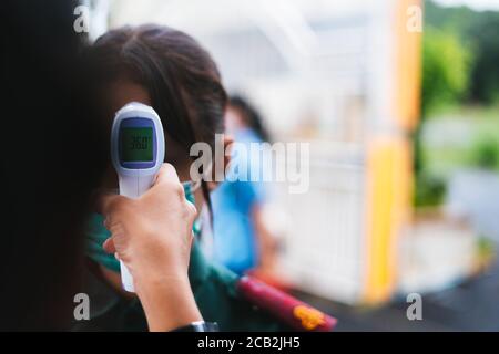 Lehrer verwenden Infrarot-Thermometer Pistole Stirn Temperatur Test zu überprüfen Schüler für Schutz Virus covid-19 Symptome in der Schule16:9 Stil Stockfoto