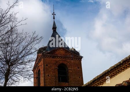 Turm der Kirche von El Burgo Ranero, mit großen Storchennestern. Eindrücke vom Camino de Santiago de Compostela in Spanien. Stockfoto