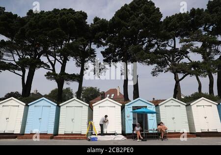 Eine Person malt ihre Strandhütte am Avon Strand in Mudeford, Dorset. Stockfoto