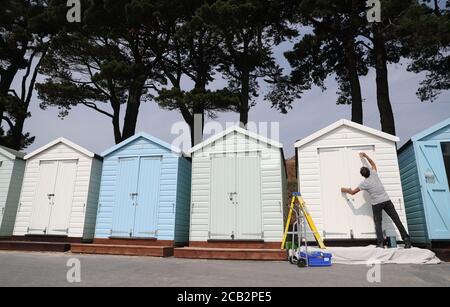 Eine Person malt ihre Strandhütte am Avon Strand in Mudeford, Dorset. Stockfoto