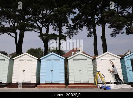 Eine Person malt ihre Strandhütte am Avon Strand in Mudeford, Dorset. Stockfoto