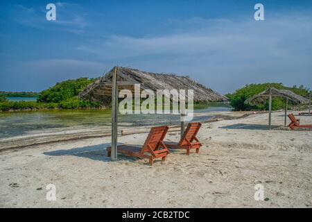 Zwei verstellbare Holzstühle unter einem Strohdach am Strand in Bonaire Stockfoto