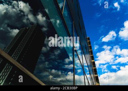 Ein tiefblauer Himmel spiegelt sich in den sauberen Glaswänden eines Gebäudes in einer Großstadt wider. Stockfoto