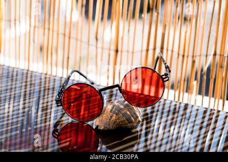 Steampunk Sonnenbrille mit roter Linse auf einem Shell-Shooting platziert Im Sommer an einem sehr sonnigen Tag Stockfoto