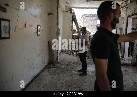 Idlib City, Syrien. August 2020. Besucher besichtigen eine Ausstellung des syrischen Künstlers Rami Abd al-Haq in einem der beschädigten Häuser in Idlib. Die Zeichnungen zeigen Figuren und Figuren, die während des syrischen Bürgerkriegs entstanden sind und Einfluss auf die Medien hatten. Quelle: Anas Alkharboutli/dpa/Alamy Live News Stockfoto