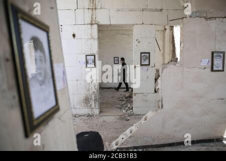 Idlib City, Syrien. August 2020. Ein Besucher besucht eine Ausstellung des syrischen Künstlers Rami Abd al-Haq in einem der beschädigten Häuser in Idlib. Die Zeichnungen zeigen Figuren und Figuren, die während des syrischen Bürgerkriegs entstanden sind und Einfluss auf die Medien hatten. Quelle: Anas Alkharboutli/dpa/Alamy Live News Stockfoto